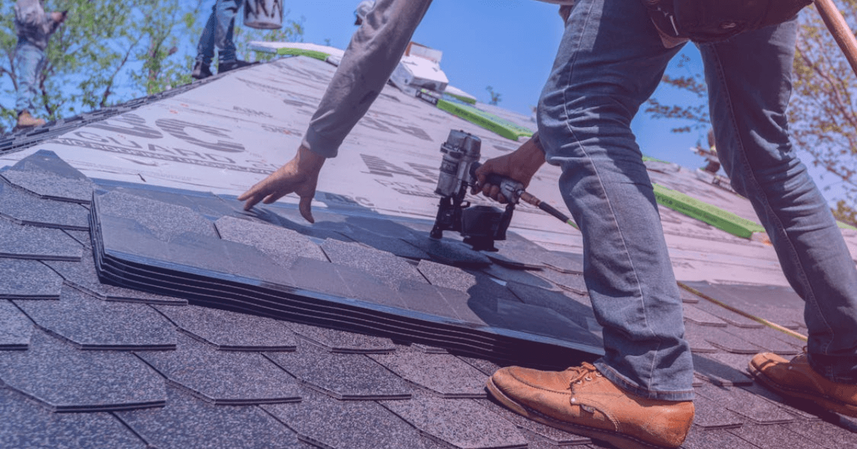 Roofer installing shingles on residential roof